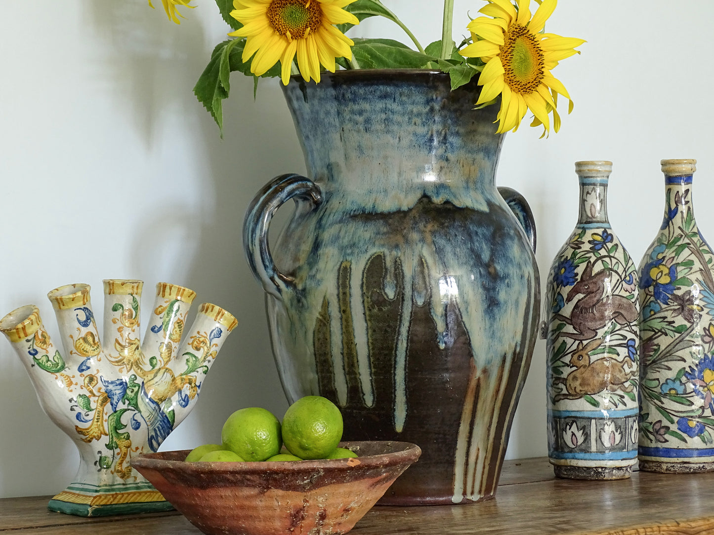 Large French vintage pottery vase with a blue glaze with Italian antique tulip vase, Iznik bottles and earthenware bowl on a sideboard