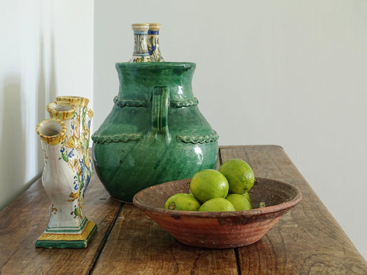French antique earthenware bowl filled with limes on a sideboard with ceramic vases in a French country house