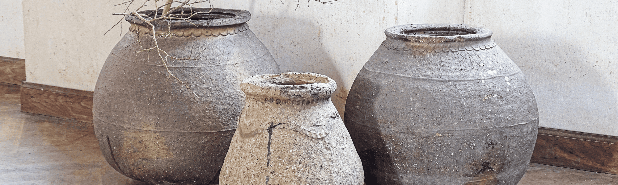 collection of French antique terracotta vessels or ponnes in a neutral room decor setting
